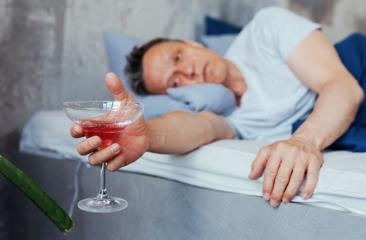 Мужчина лежит в кровати с бокалом